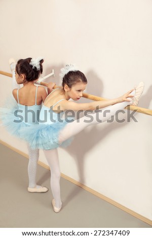 Two little ballerinas stretching and practicing ballet and using stick on the wall. Photo inspired with famous paint of Edgar Degas