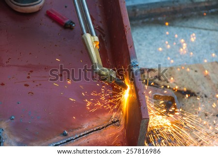 Metal Cutting With Acetylene Gas. Workman is working by use torch cut the iron in factory. Spark splash around the ground.