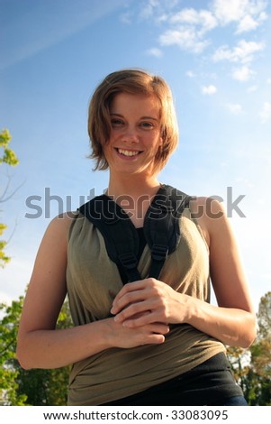 Female student holding the straps of her backpack smiling at camera