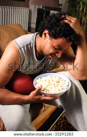 A man with a football and popcorn holding his head after a bad call