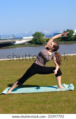 Woman doing a yoga side stretch in a green space outside the city