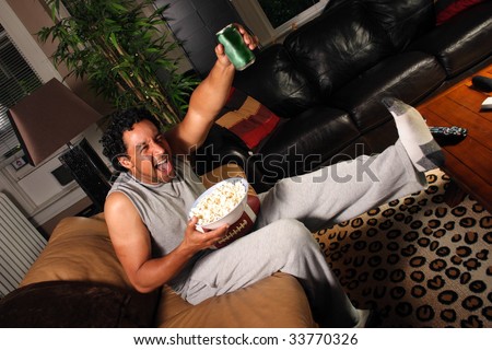 A man with football, popcorn and drink excited about a score for his team