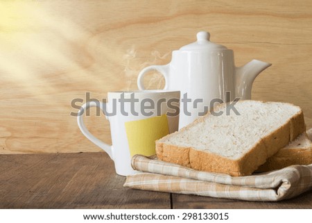 Coffee and bread on wooden background with sunshine in morning