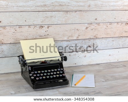 Old Technology, typewriter with notepad and  pencil on an old shabby wood effect desk and background
