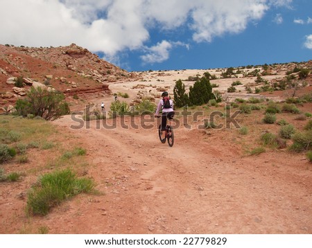 Three mountain bikers bike off into the distance on a beautiful desert trail