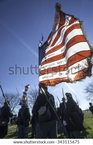 GETTYSBURG,PA/USA - NOVEMBER 21, 2015: Group of unidentified Union Civil War re-enactors gather on the Gettysburg Battlefield with U.S. flag imprinted with the names of several Civil War Battles.