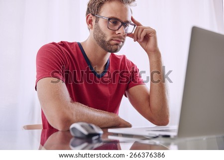Young man staring at screen trying to figure out how he is going to overcome the problems that he has noticed
