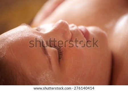 Close up image of a young girl\'s face as she relaxes with her eyes closed, while she waits for her facial mask to be removed
