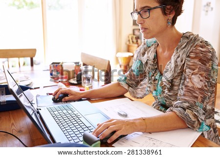 Mature business woman frustrated by her outdated laptop computer while working at her desk in her home office