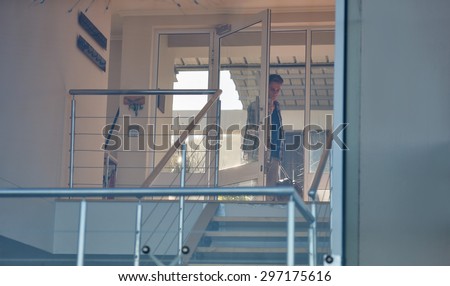 Image of a young broker walking through the glass front door of his luxurious modern penthouse