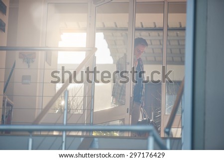 Successful young businessman with his own style, walking into his modern beach house with flare from behind
