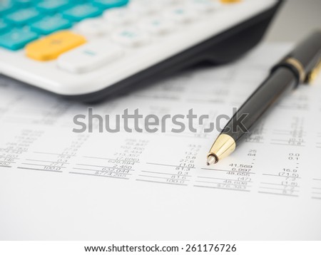 A close-up shot of a calculator.  A printed balance sheet and a pen are also visible.