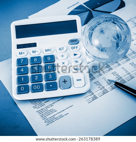 A close-up shot of a calculator.  A printed balance sheet and a pen are also visible.