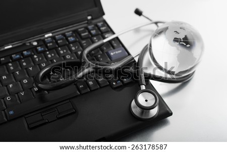 Glass globe and stethoscope on a computer keyboard.