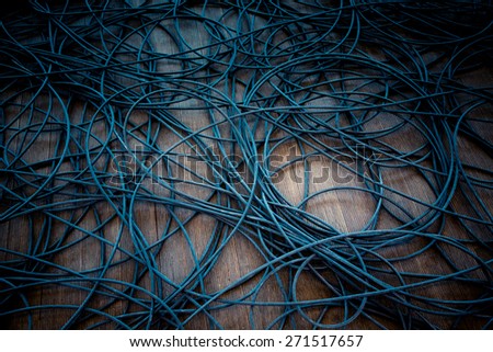 Network chaos of colorful cables on the wooden floor.