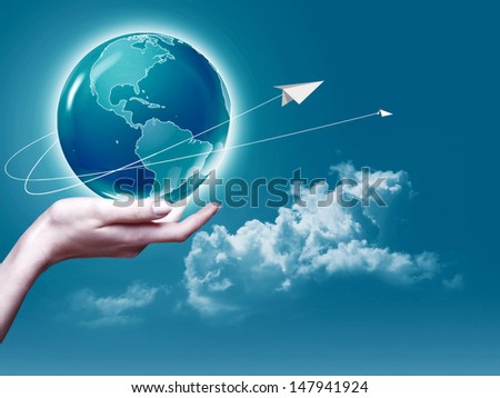 Female arm holding Earth  globe against blue skies, environmental backgrounds