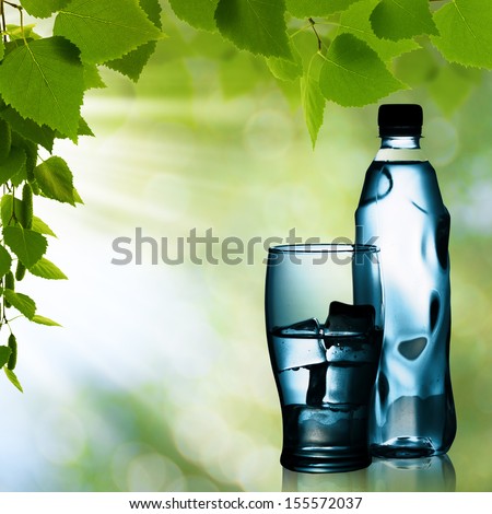 Spring mineral water bottled with glass and ice against natural backgrounds