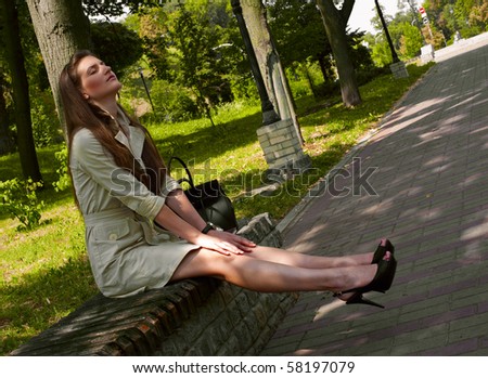 summer heat at midday in the city. young woman relaxing on the park bench