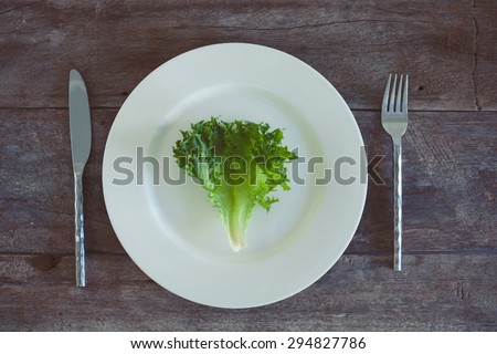 Letucce salad leaves on wooden background. Healthy food illustration. Salad ingridient on the plate.