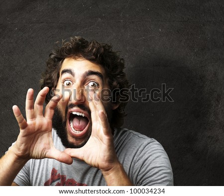 portrait of a young man screaming against a grunge wall
