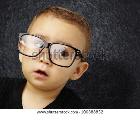 portrait of a kid wearing glasses against a grunge wall
