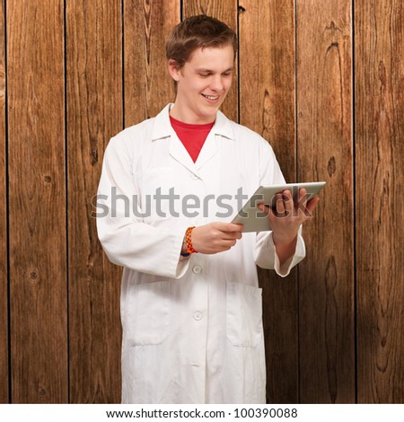 portrait of a young academic holding a digital tablet against a wooden wall