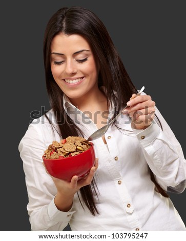 portrait of a healthy young woman eating cereals over a black background