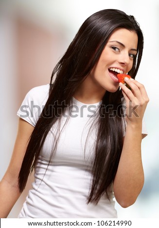 portrait of a young woman eating a strawberry indoor
