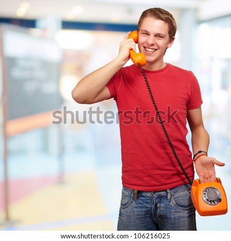 portrait of a young man talking with a vintage telephone indoor