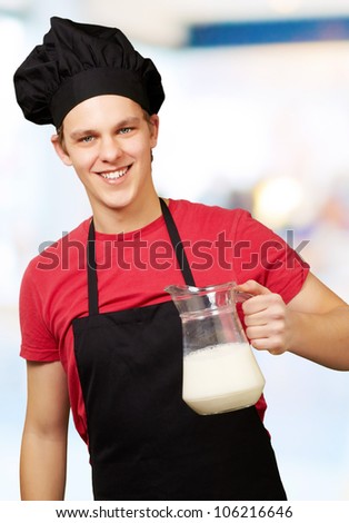 portrait of a young cook man holding a milk jar indoor