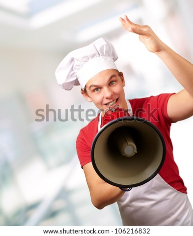 portrait of a happy cook man shouting using a megaphone indoor