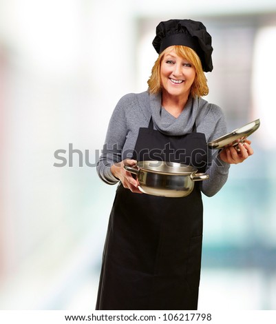 Middle aged cook woman holding a sauce pan indoor