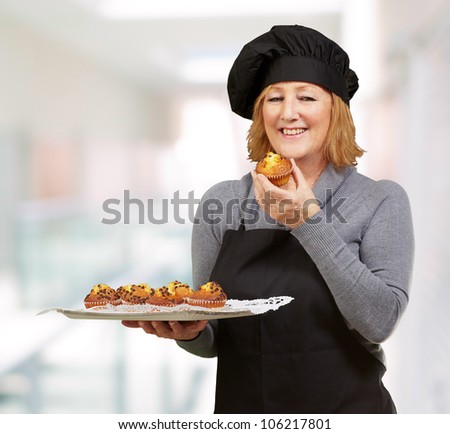 portrait of a middle aged cook woman holding a homemade muffin indoor