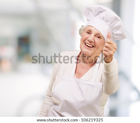 portrait of a cook senior woman doing a good gesture indoor