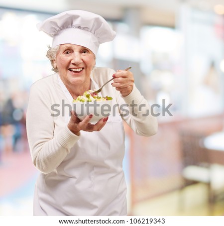 portrait of a senior cook woman eating a salad at a restaurant