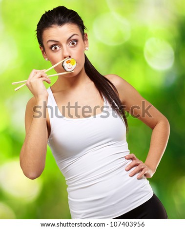 young woman covering her mouth with a sushi piece against a nature background