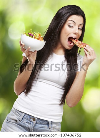 woman choosing a slice of pizza instead of a salad against a nature background
