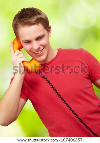 portrait of a young man talking on a vintage telephone against a nature background