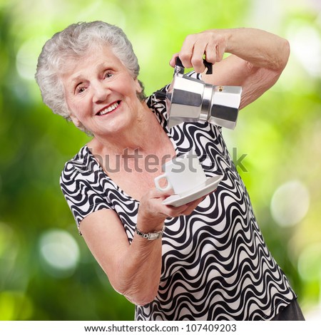 portrait of a vitality senior woman serving a tea cup against a nature background