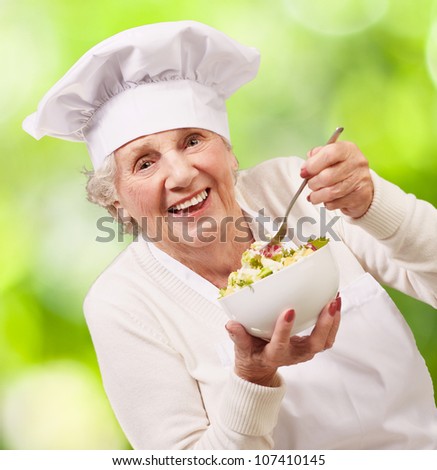 portrait of a senior cook woman eating a salad against a nature background