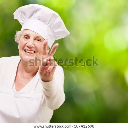 portrait of a cook senior woman doing a good gesture against a nature background