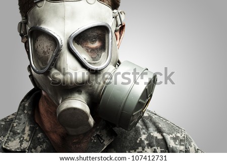 portrait of a young soldier wearing a gas mask against a grey background