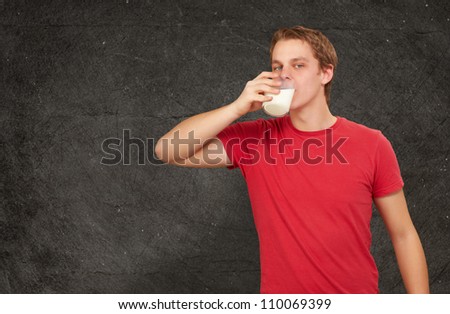 portrait of young man drinking milk against a grunge wall