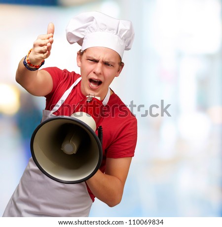 portrait of young cook man screaming with megaphone and gesturing against a nature background