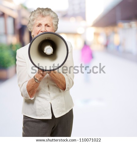 portrait of senior woman screaming with megaphone at city