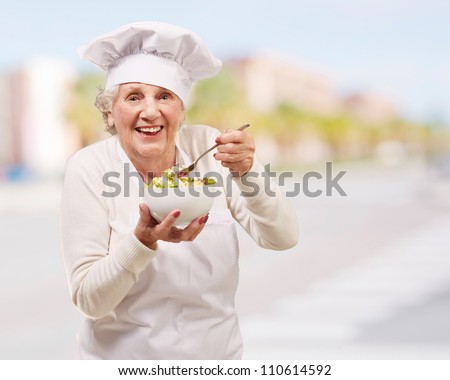 portrait of senior cook woman eating salad at city