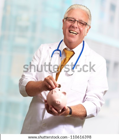 Male Doctor Putting Coins In A Piggy Bank, Indoor