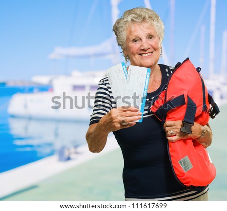 Senior Woman Standing With Tickets And Bag With Boat In The Background