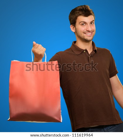 Portrait Of A Young Man Holding A Handbag On A Blue Background