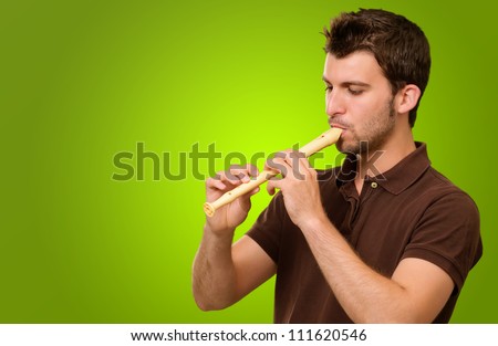 Portrait Of A Young Male Playing Flute On Green Background
